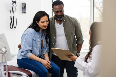 Doctor holds medical chart to show her patient and partner her test results