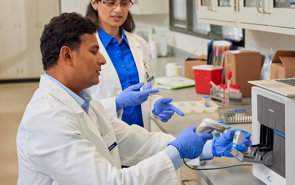 a male and a female researchers scanning cepheid test cartridges