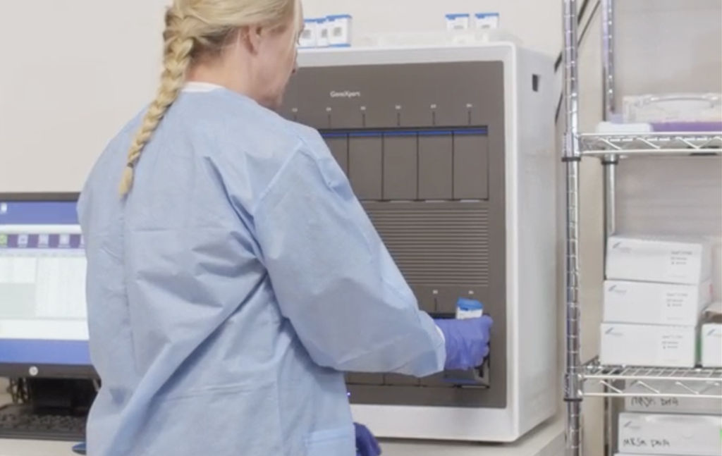a lab person inserting a test cartridge in a GeneXpert system